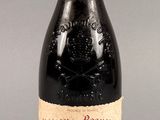 une bouteille de vin rouge posée sur une table, sur fond gris