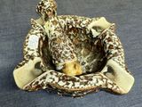 a giraffe statue sitting in a bowl on a bed