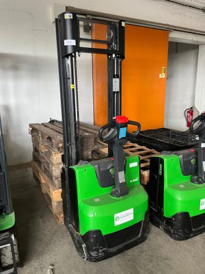 deux chariots élévateurs verts et noirs dans un entrepôt