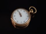 gros plan d'une montre de poche en or sur une surface noire