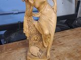 une statue représentant une femme tenant un poisson sur une table en bois