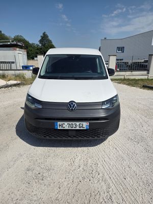 La camionnette blanche est garée sur le chemin de terre devant un immeuble.
