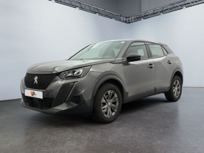 La voiture grise est garée dans une grande pièce aux murs blancs.