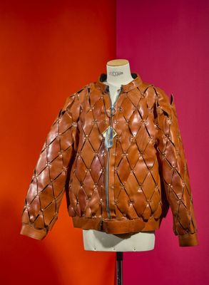 brown quilted leather jacket on mannequin stand against red wall