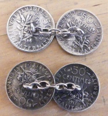 trois pièces d'argent munies de chaînes, posées sur une table en bois