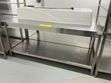 une table en acier inoxydable sur laquelle est posé un récipient en plastique