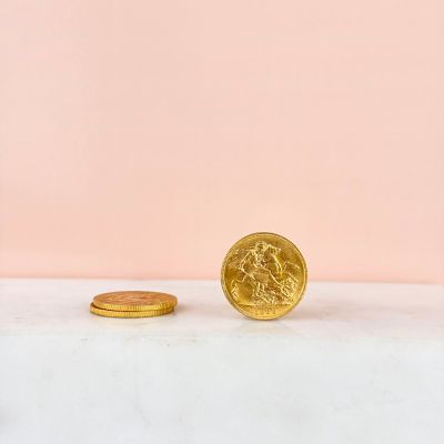 a gold coin next to a gold coin on a pink background