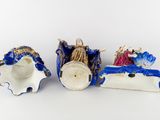 three porcelain figurines of people in a boat and a man in a boat