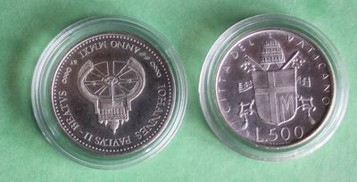 the two coins are in a clear plastic container on a green surface