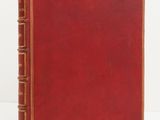 un vieux livre rouge posé sur une table blanche