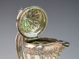 a silver vase with a lid that has a flower design on it