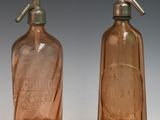 deux bouteilles en verre brun munies d'un bec verseur en métal, placées l'une à côté de l'autre