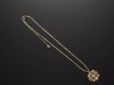 a gold necklace with a flower pendant on a black background