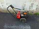 a red and black power washer sitting on the pavement