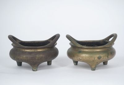 paire de pots en bronze avec des anses et des pieds, sur fond blanc
