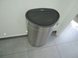 a trash can in the corner of a bathroom