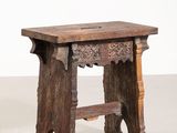 une vieille table en bois dont le plateau sculpté repose sur un plan de travail blanc
