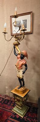 une statue représentant un homme tenant un candélabre posé sur une table