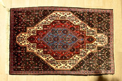 une photo d'un tapis posé sur un parquet, avec l'ombre d'une personne debout à côté