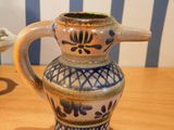 a blue and white vase sitting on a table next to a cup