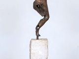 statue d'un homme tenant une raquette de tennis, posée sur un socle blanc