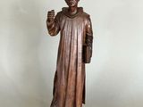 wooden statue of a monk holding a book and a candle