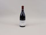 une bouteille de vin rouge posée sur une table blanche