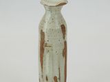 a small white vase with brown spots on it