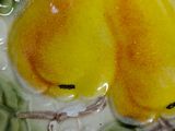 two yellow pears sitting on a plate with green leaves