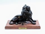 statue en bronze représentant un lion, posée sur un socle en marbre, sur fond blanc