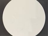 a white plate sitting on the floor in front of a black wall