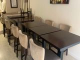 Des tables et des chaises sont alignées dans une pièce où est accroché un tableau au mur.
