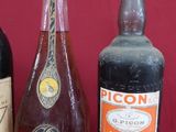 trois bouteilles d'alcool sont alignées sur une surface rouge