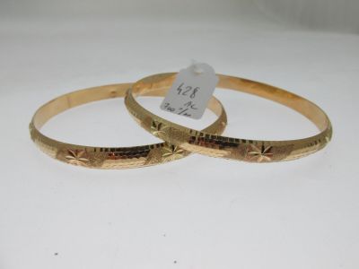 deux bracelets en or présentant des motifs gravés sur un fond blanc