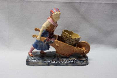 figurine représentant une femme poussant une brouette sur laquelle est posé un panier