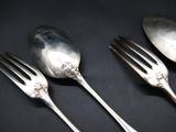 three spoons and two forks on a black surface