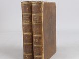 two old books sitting on top of each other on a white surface