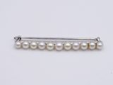 a close up of a white pearl hair pin on a white surface