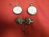 two clocks that are attached to a chain on a red cloth
