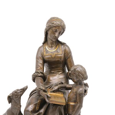 statue en bronze représentant une femme assise sur une chaise avec un chien