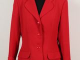 La veste rouge est présentée sur un mannequin posé sur un socle noir.