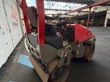 an image of a red and black road roller parked in a parking lot