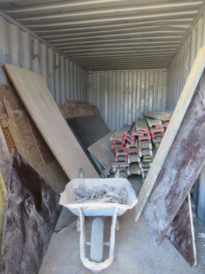 un tas de bois dans un conteneur où se trouve une brouette