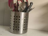 a cup that has some scissors in it on a shelf