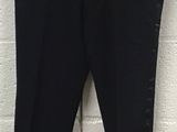 black pants hanging on a hanger in front of a white brick wall