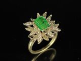 an emerald and diamond ring on a black surface