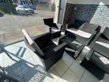 une photo d'une terrasse avec des chaises en osier et une table basse