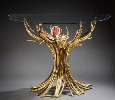 une table en verre ornée de branches dorées et dotée d'un plateau en verre