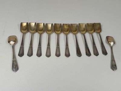 six spoons and a fork are lined up on a white surface