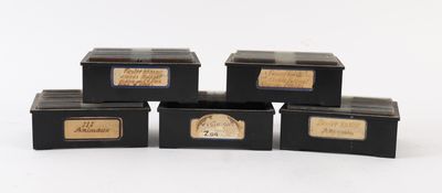 quatre boîtes noires ornées d'étiquettes dorées sont empilées les unes sur les autres